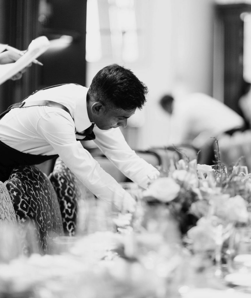 Kellner deckt ein Tisch mit vielen Blumen